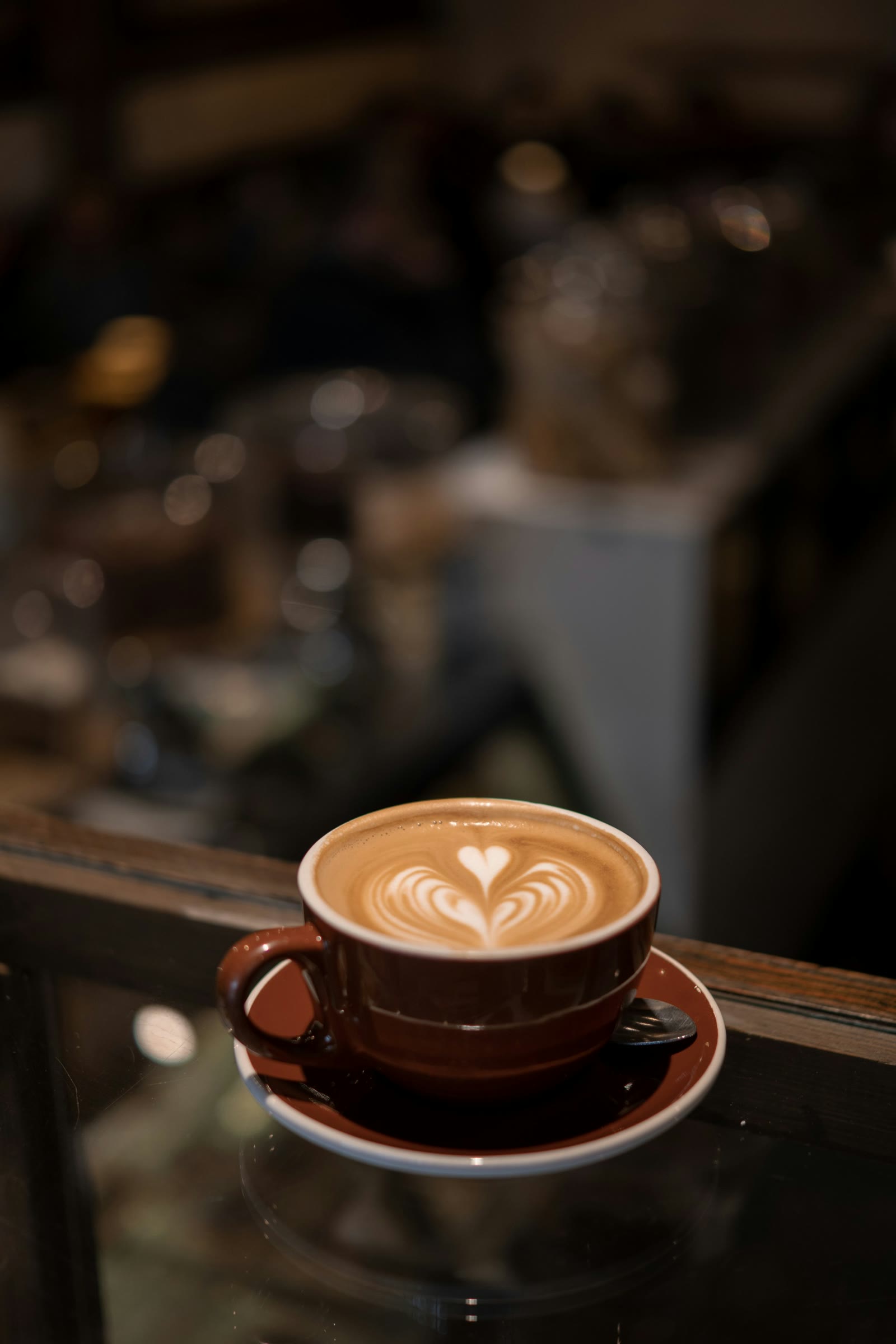 A cappuccino with a heart in a brown cup, glowing on a dark counter
