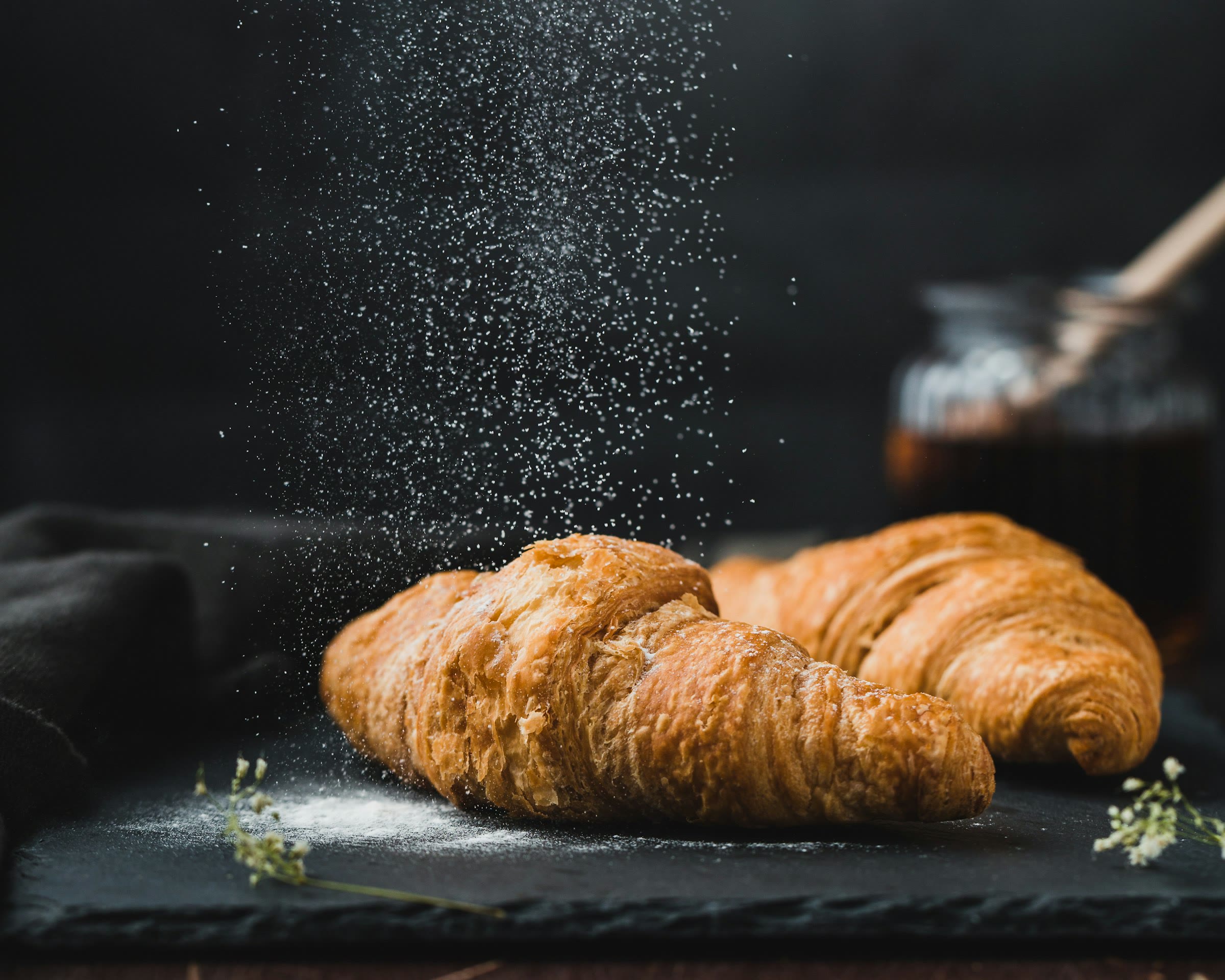 Croissants on dark slate under a fine dusting of sugar
