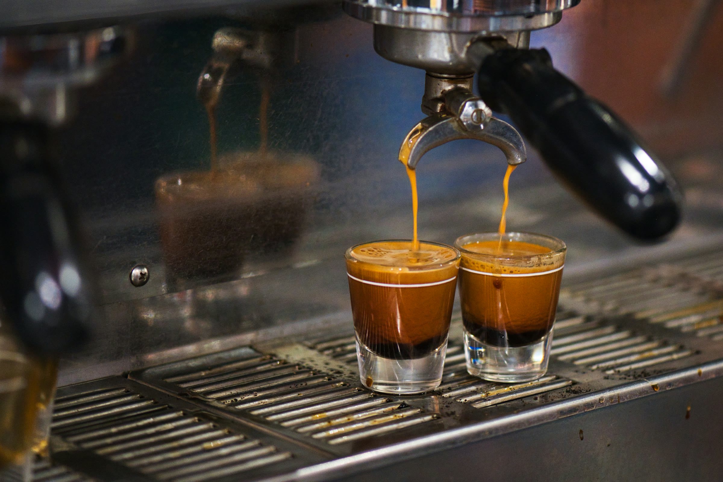 Two espresso shots pulling into small glasses on a machine's drip tray