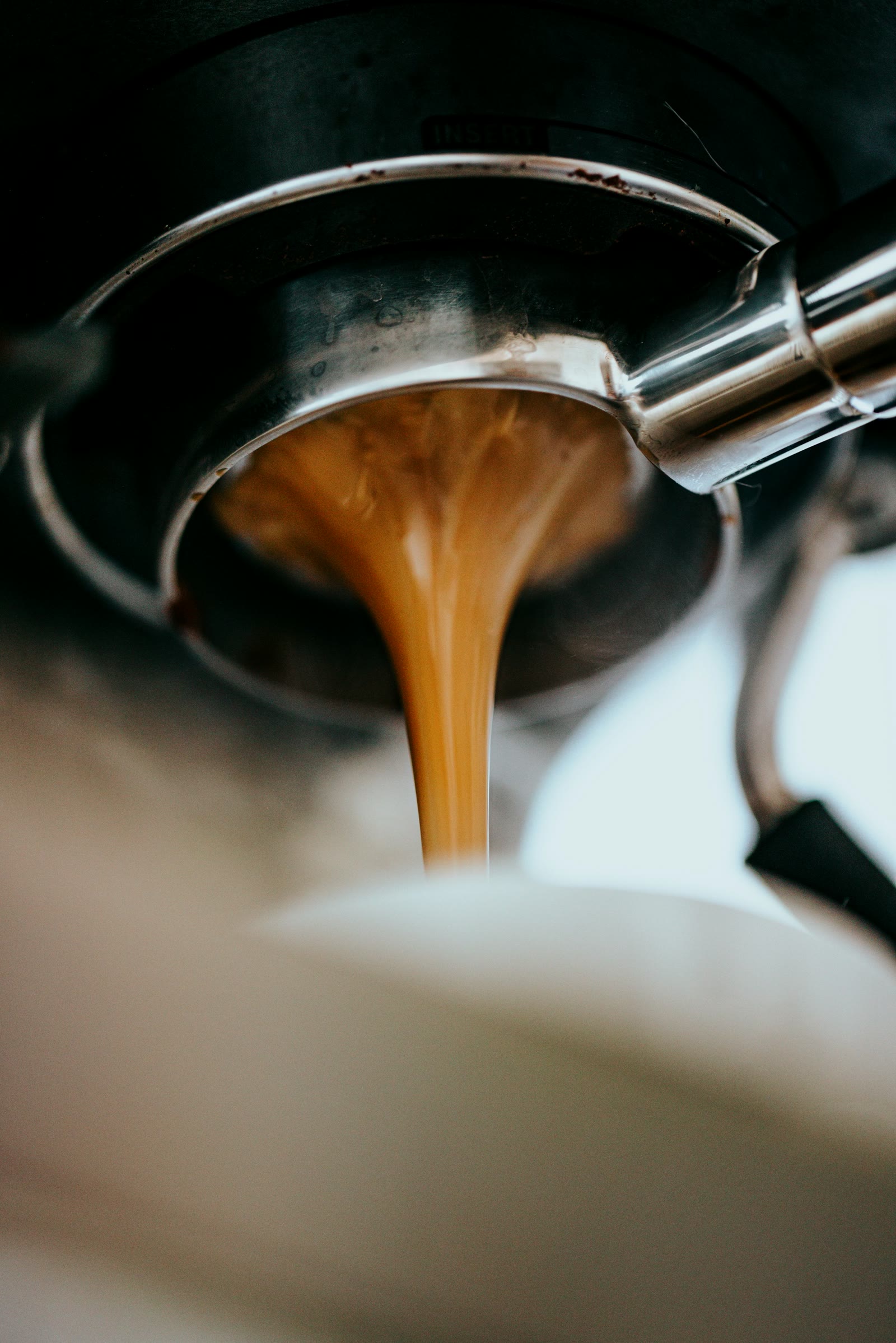 Espresso pouring from a bottomless portafilter in a thick caramel ribbon