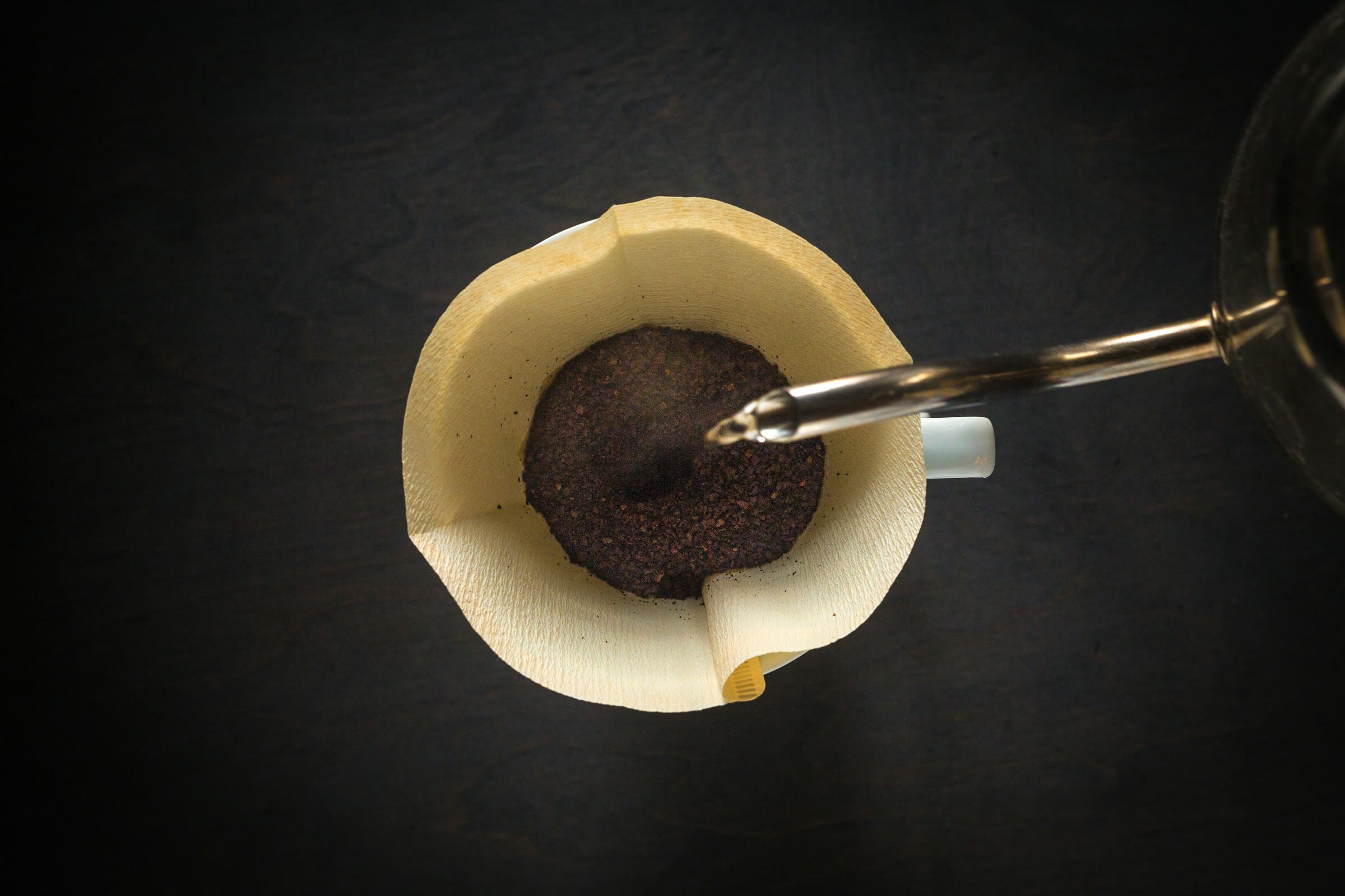 Water poured onto coffee grounds in a paper filter, seen from above