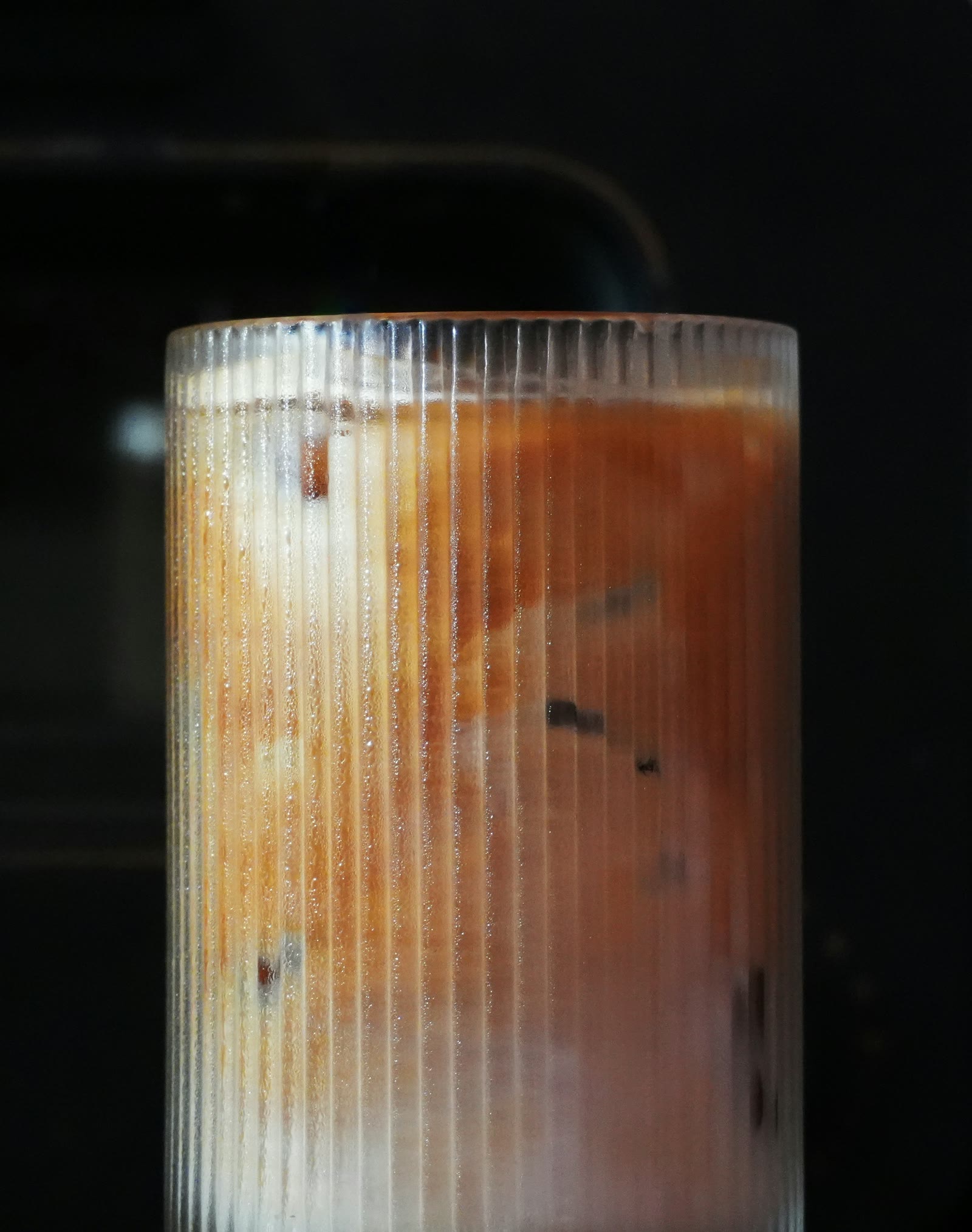 Iced coffee and milk marbling inside a tall ribbed glass