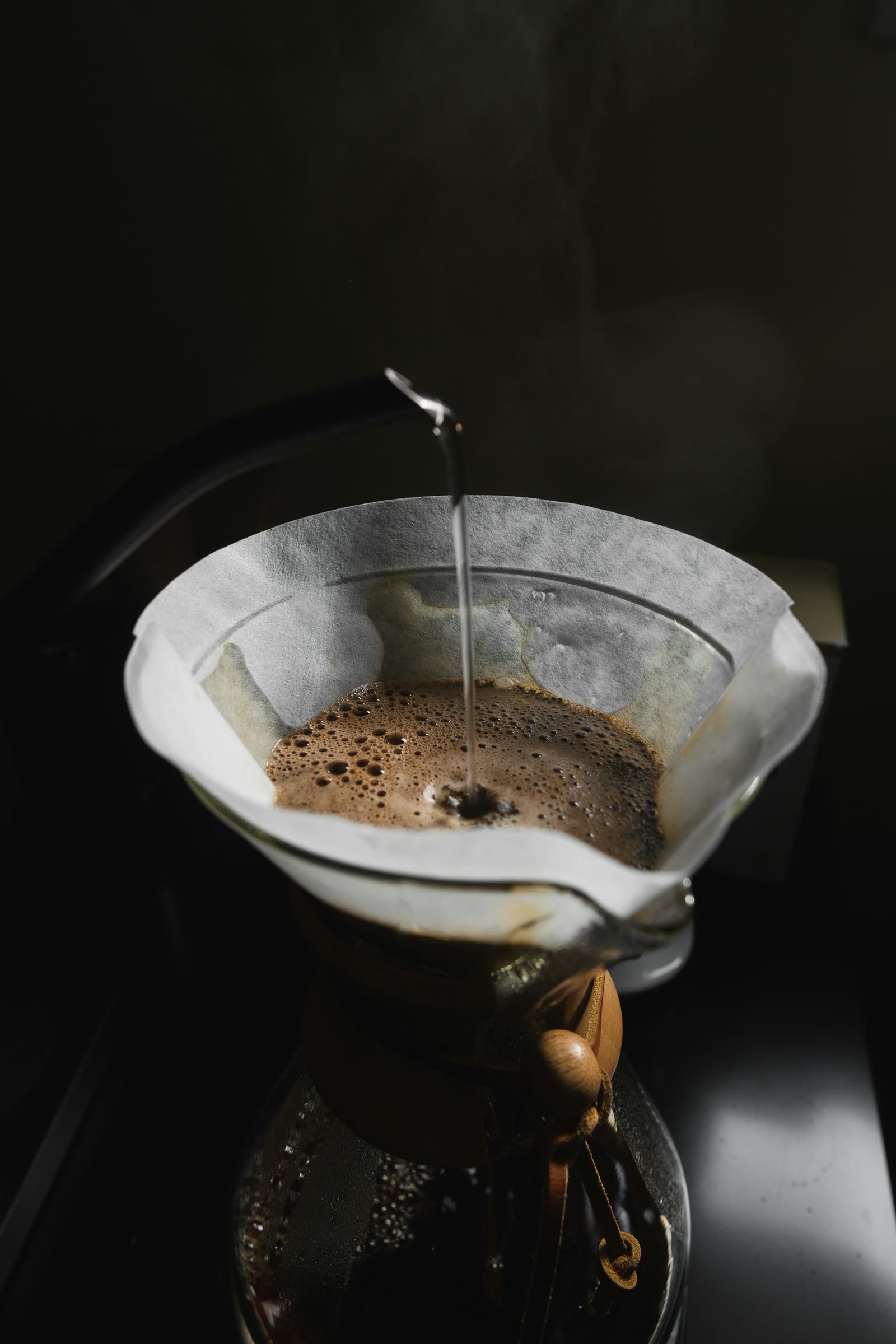 A thin stream of water falling into a paper pour-over filter